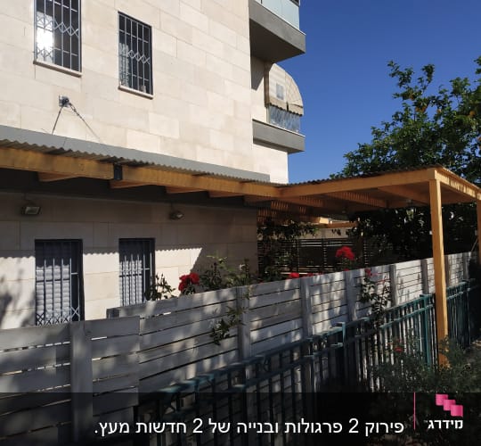 פרגולה מעץ ליד גדר עץ בגינה